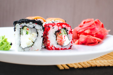 on the plate is white, lined with different rolls, sushi