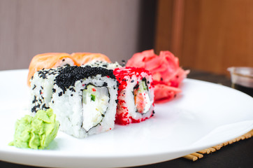 on the plate is white, lined with different rolls, sushi