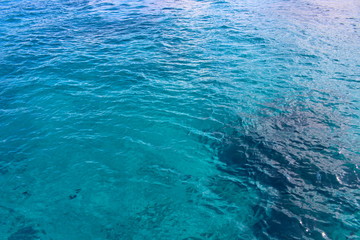 The surface of the crystal clear sea water blue and azure colors on a summer day. The pattern of the waves creates a smooth surface texture. Soft focus.