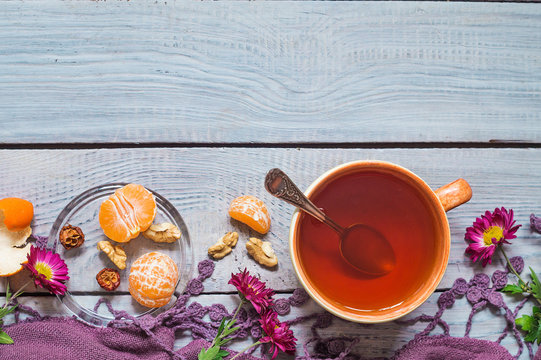 Cup of tea, flowers and tangerine on a white wooden table