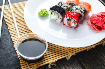 on the plate is white, lined with different rolls, sushi