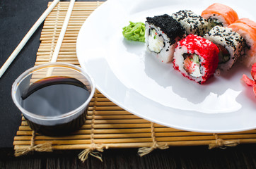 on the plate is white, lined with different rolls, sushi