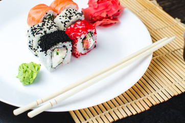 on the plate is white, lined with different rolls, sushi