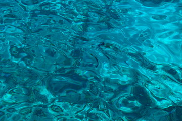 Colorful pattern transparent sea water of turquoise color. In the water of visible floating fish.