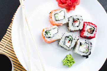 on the plate is white, lined with different rolls, sushi