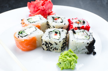 on the plate is white, lined with different rolls, sushi