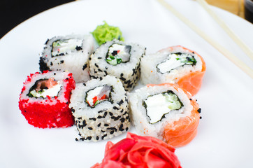 on the plate is white, lined with different rolls, sushi