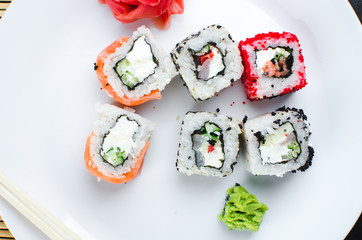 on the plate is white, lined with different rolls, sushi