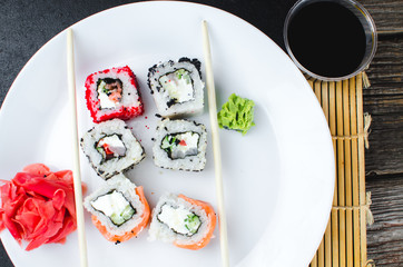 on the plate is white, lined with different rolls, sushi