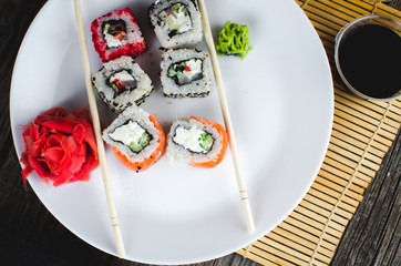 on the plate is white, lined with different rolls, sushi