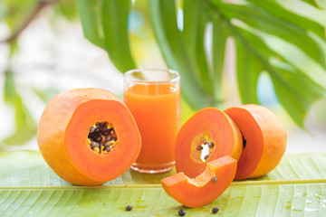 Tropical exotic papaya fruit and glass jar with smoothie shake juice drink outdoors with palm leaves