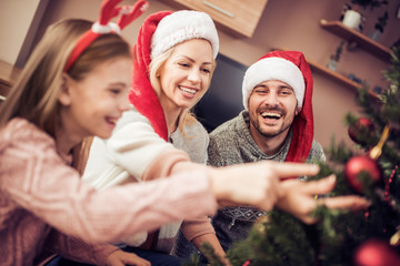 Fototapeta premium Young girl helping decorating the Christmas tree