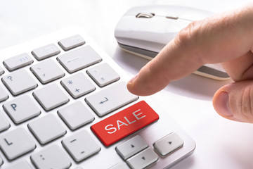 Finger pressing computer button with red sale sign