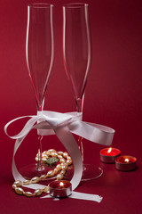 Valentines setup with two champagne glasses tied with a bow accompanied by candles and a pearl necklace - 182741922