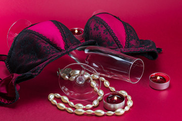 Valentines setup with erotic lingerie placed in between champagne glasses and next to candles, with a pearl necklace - 182741925