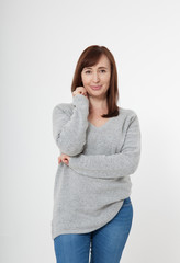 Thinking attractive middle aged woman with folded arms on grey background. Menopause and health care.