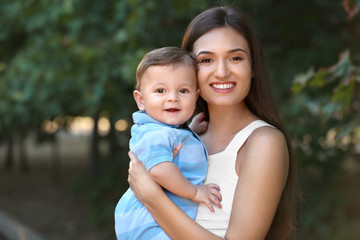 Beautiful young mother holding cute baby boy, outdoors