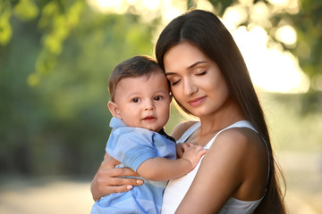 Beautiful young mother holding cute baby boy, outdoors