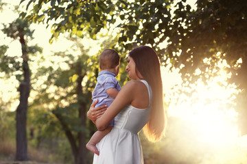 Beautiful young mother holding cute baby boy, outdoors