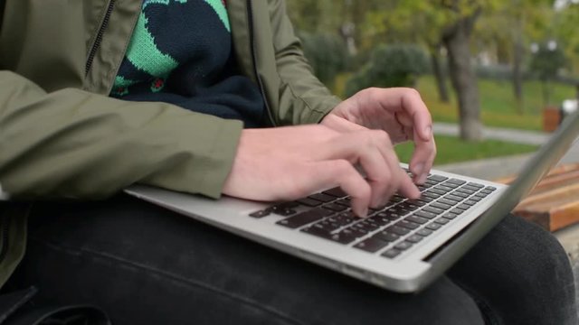 Guy and Girl Students with Laptop on Bench in Park write notes, read a Textbook
