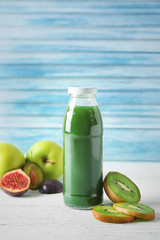 Bottle with fruit juice on table against light wall