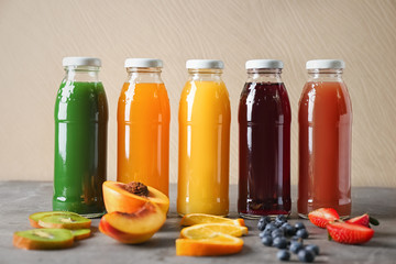 Bottles with fruit juices on table against light wall