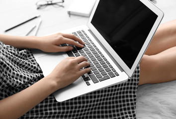Woman using laptop while sitting on floor indoors