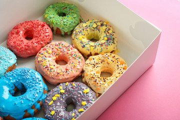 Tasty glazed donuts in box on color background
