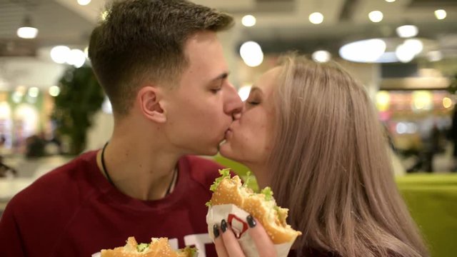 Guy and Girl Students lovers kissing and eating Burgers, Potato Fries and Cola
