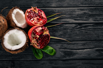 Pomegranate and coconut. Fresh fruits. On a wooden background. Top view. Free space for text.