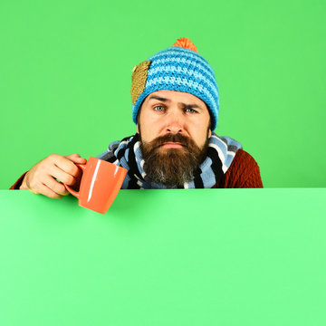 Hipster with confused face has warm tea or coffee