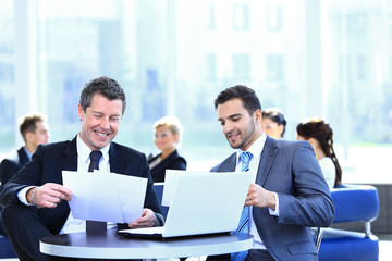 business partners discussing a new project, sitting in the lobby of the office.