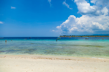 Tropical sandy beach with boats and people in a sea. Gili Trawangan, Indonesia
