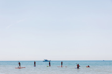People practice Stand Up Paddleboarding outside the Brighton beach