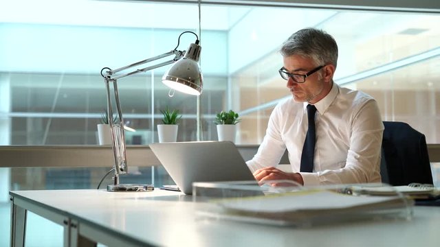Businessman in office working at desk on laptop computer