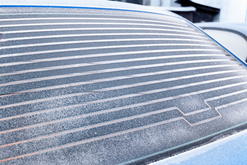 Rear car window covered with frost, warmed defroster.
