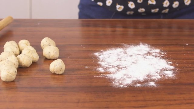 A Lady spreading Flour on Wooden Table and Rolling Out Small Poori - Closeup Shot 
