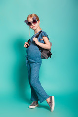 little girl with a tail in stylish clothes and sunglasses on blue background