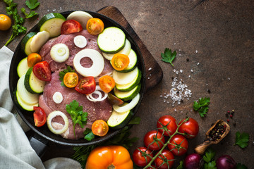 Raw pork meat with vegetables in the pan. Top view copy space.