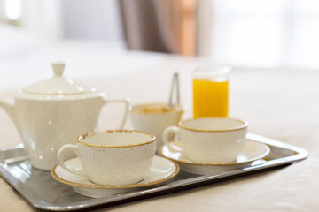 Two white mugs on a tray white bed, breakfast concept