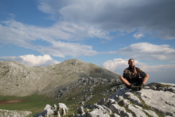 Natural man meditates on a mountain peak