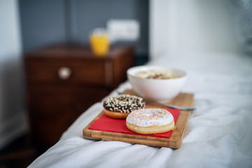 Close up of breakfast or dinner on wooden saucer left on the bed at home or hotel.