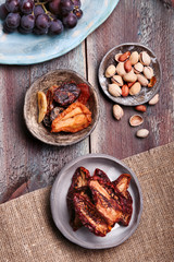 Dried fruits and nuts in pottery bowls on old wooden table