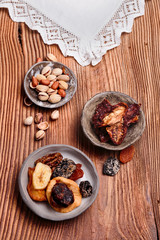 Dried fruits and nuts in pottery bowls on old wooden table