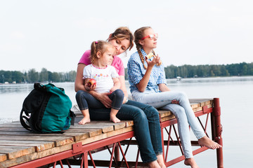 Family spending time together sitting on jetty over the lake in the summertime