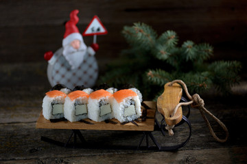 Homemade sushi with salmon on small sleigh, Christmas background