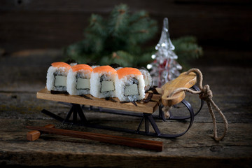Homemade sushi with salmon on small sleigh, Christmas background