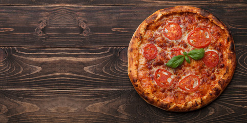 Rustic homemade pizza with tomatoes, cheese and basil. Top view on wooden table. Space for text