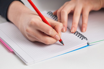 young woman hands hold opened notebook pages with red pencil