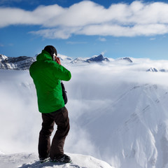 Fototapeta na wymiar Skier at top of mount and snowy mountains in haze